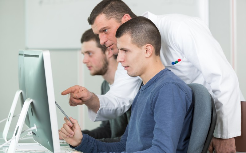 Two employees discuss in front of the computer