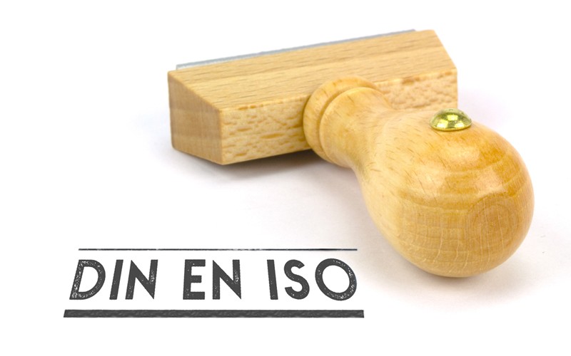 DIN EN ISO wood stamp in front of a white background. 