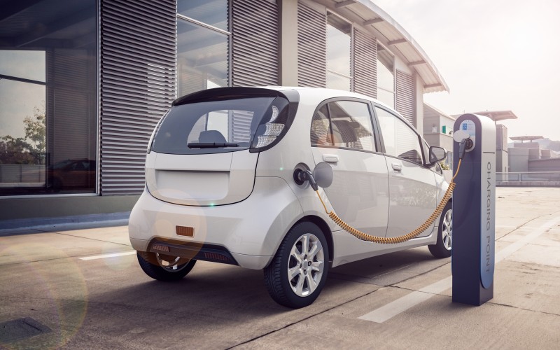 White electric car in a parking lot at the charging station