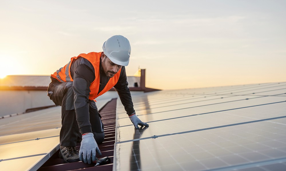 A worker is fixing solar panels on the roof