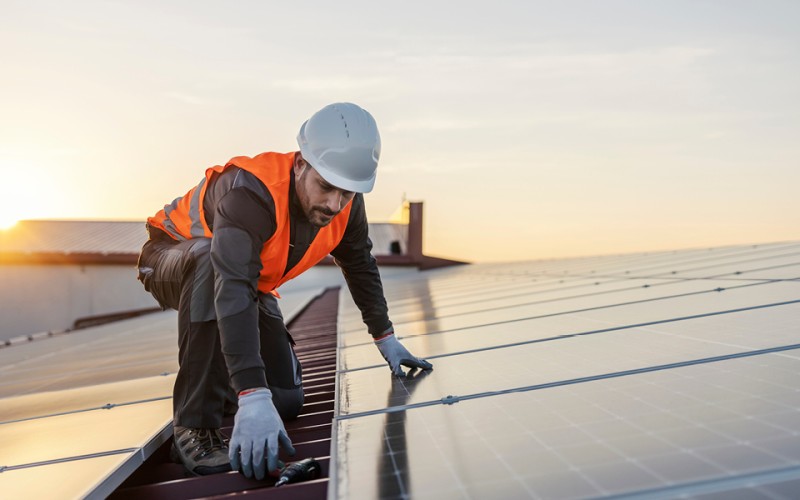 A worker is fixing solar panels on the roof