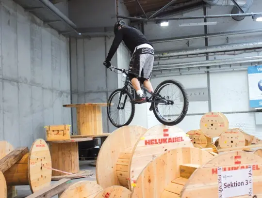 Bike trial rider jumps over cable drums