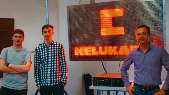 Two pupils and their teacher in front of the LED wall