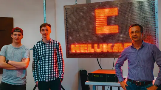 Two pupils and their teacher in front of the LED wall Two pupils and their teacher in front of the LED wall