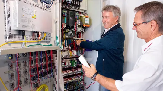 Two men test the wiring inside the control cabinets 