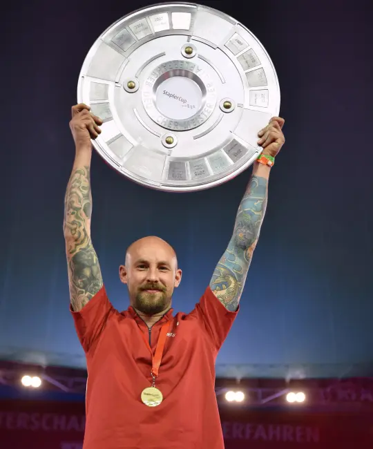 Jörg Klößinger raises a trophy in the air