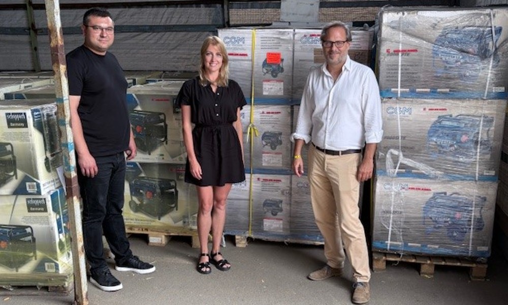 3 personen staan in een magazijn voor de gedoneerde generatoren
